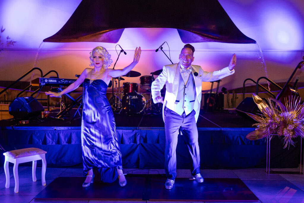 two people singing on stage at a party