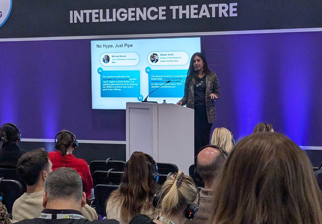 Woman on stage, standing at a podium, giving a conference presentation