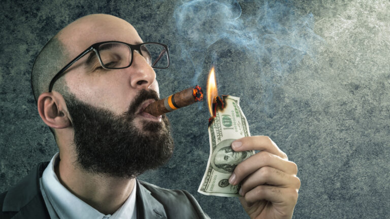 Man smoking cigar lighting money on fire